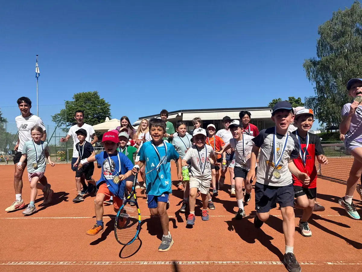 Junge Tennisspielerinnen und -spieler des TC Kilchberg mit Schlägern auf dem Sandplatz