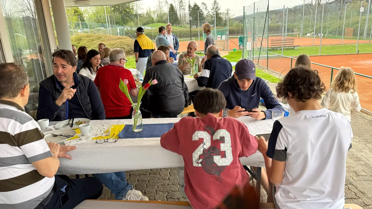 Gäste an langen Tischen im Clubhaus beim Brunch