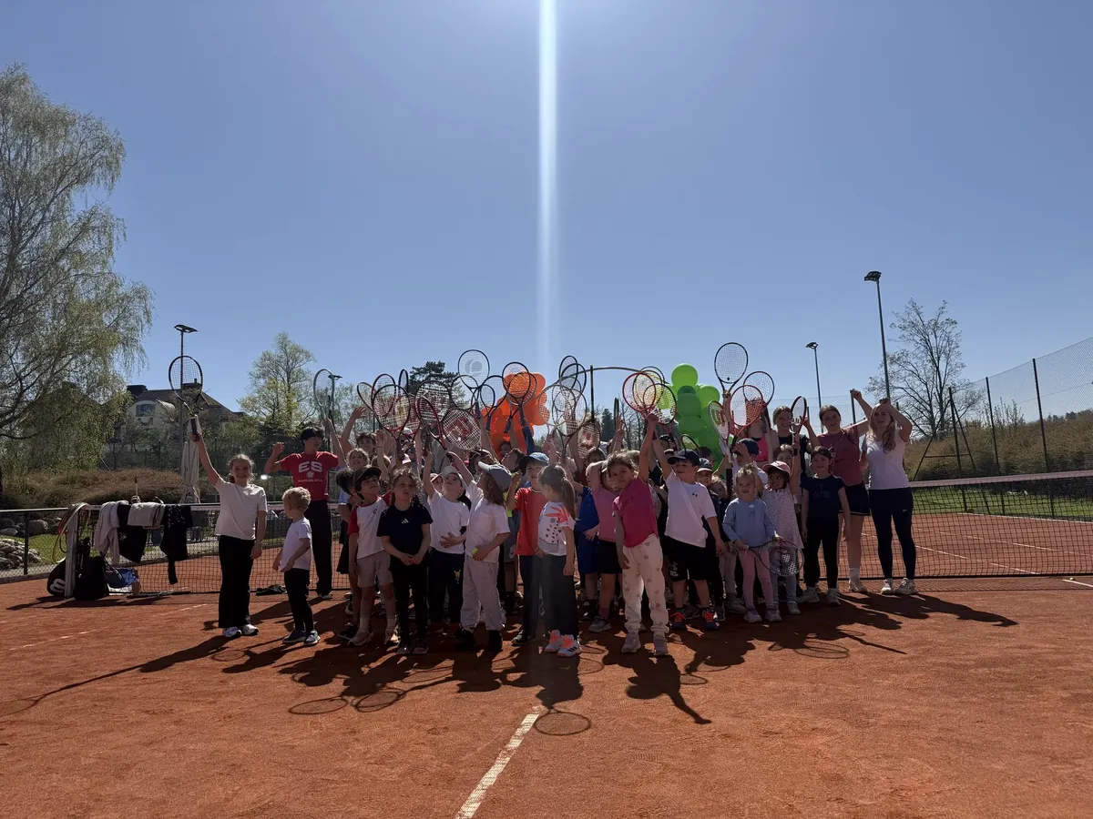 Grosse Gruppe Kinder mit Schlägern auf dem Sandplatz